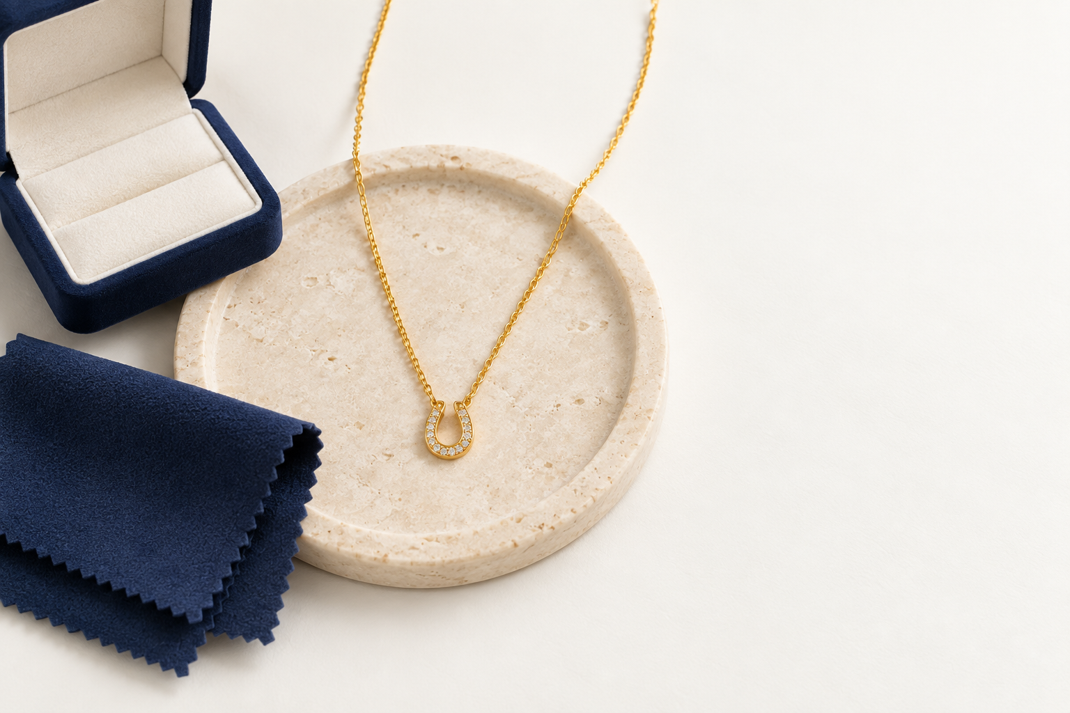 Pavé horseshoe necklace arranged with a soft care cloth and jewelry box