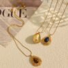 Gold-tone sculpted pendant necklaces with tiger's eye and lapis lazuli on a warm ivory surface Gold-tone sculpted pendant necklaces with tiger's eye and lapis lazuli on a warm ivory surface