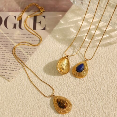 Gold-tone sculpted pendant necklaces with tiger's eye and lapis lazuli on a warm ivory surface Gold-tone sculpted pendant necklaces with tiger's eye and lapis lazuli on a warm ivory surface