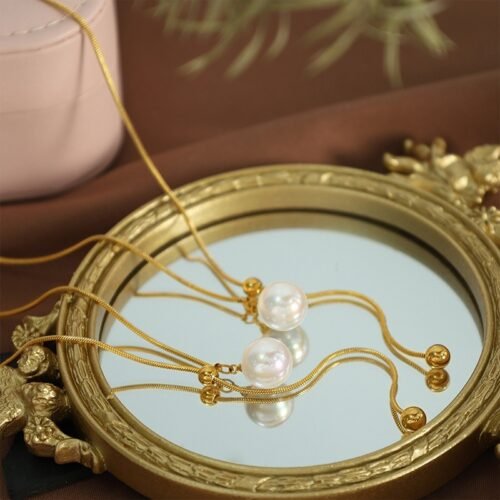 Pearl Drop Adjustable Y Necklace product image 1 Gold-tone pearl drop adjustable Y necklaces arranged on an antique mirror