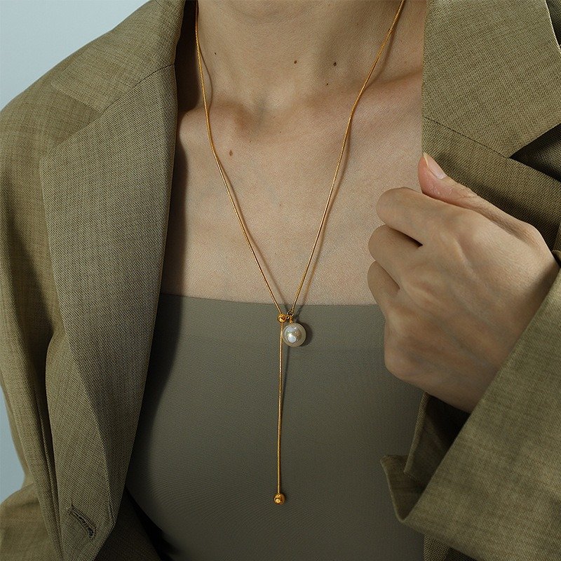 Gold-tone pearl drop necklace styled with a neutral jacket